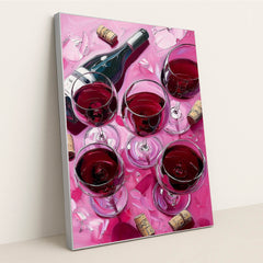 This artwork shows a wine bottle and five glasses of red wine with corks and petals on a pink surface, in a silver frame.
