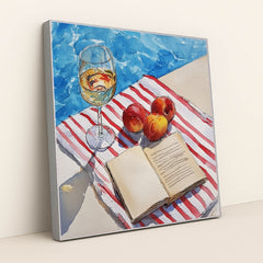 This artwork features a wine glass, peaches, and an open book on a striped towel beside a pool, in a silver frame.