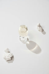 Gül Işık - A glass of champagne surrounded by elegant marble busts on a clean white background.