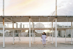 Mikhail Nilov - A woman sits alone on a swing in a deserted industrial area at twilight, evoking solitude.