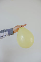 Cup of  Couple - A hand carefully holding a yellow balloon, creating a minimalist and playful composition against a white background.