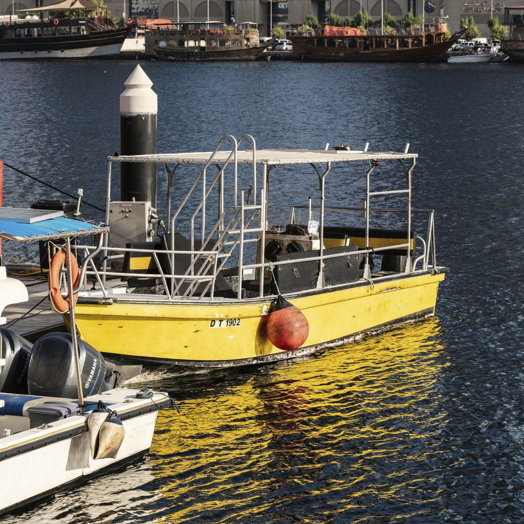 aboodi vesakaran - A vibrant yellow boat docked at a busy marina harbor in Dubai, United Arab Emirates.