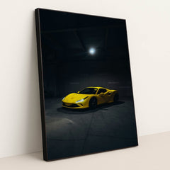 This photo shows a yellow Ferrari sports car spotlighted in a dark, empty garage, in a black frame.