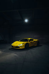 Ferrari F8 Tributo in the Spotlight, yellow car wall art illuminated in a dark industrial space.