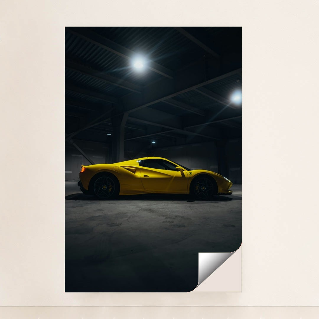 This photo shows a yellow Ferrari sports car in a dimly lit industrial garage, side view captured under overhead lights, minimalist unframed style.